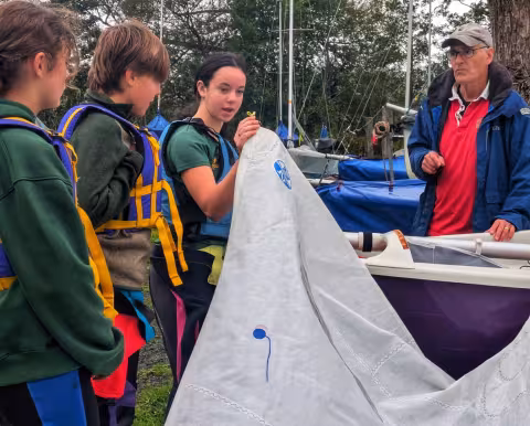 "The jib-tack is attached to the furler on the bow-point like this" - a young Assistant Instructor demonstrates boat rigging, coached by Chief Instructor, Richard McCulloch AIs learning how to instruct in boat-rigging with Chief Instructor, Richard McCulloch.